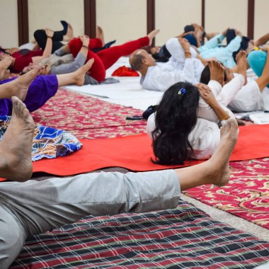 Yeni Delhi, Hindistan, 19 Haziran 2022 - Balaji Tapınağı, Vivek Vihar, Uluslararası Yoga Günü, tapınaktaki yoga sınıfına katılan büyük bir grup yetişkin için grup yoga oturumu