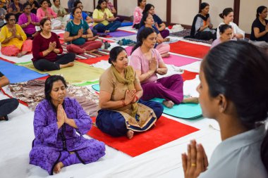 New Delhi, India, June 19 2022 -Group Yoga exercise session for people of different age groups in Balaji Temple, Vivek Vihar, International Yoga Day, Big group of adults attending yoga class in temple