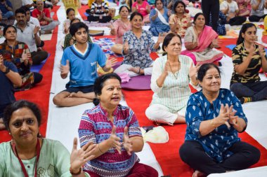 New Delhi, India, June 19 2022 -Group Yoga exercise session for people of different age groups in Balaji Temple, Vivek Vihar, International Yoga Day, Big group of adults attending yoga class in temple