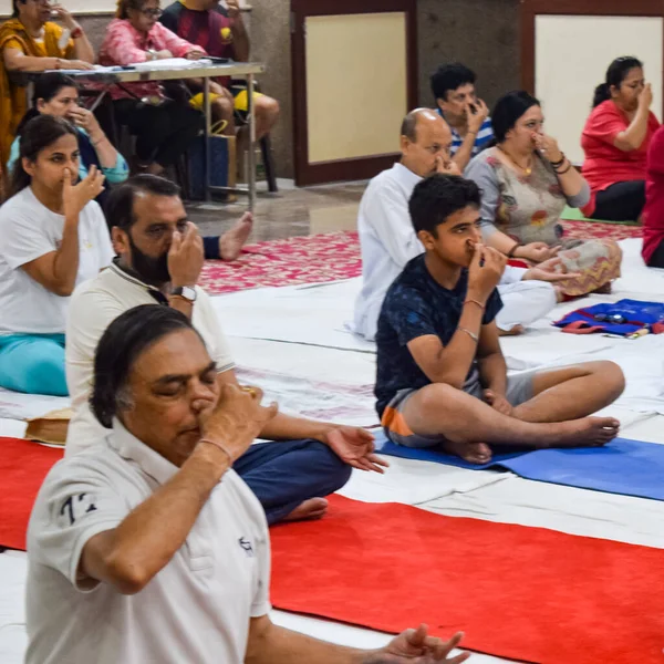 Yeni Delhi, Hindistan, 19 Haziran 2022 - Balaji Tapınağı, Vivek Vihar, Uluslararası Yoga Günü, tapınaktaki yoga sınıfına katılan büyük bir grup yetişkin için grup yoga oturumu