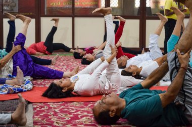 New Delhi, India, June 19 2022 -Group Yoga exercise session for people of different age groups in Balaji Temple, Vivek Vihar, International Yoga Day, Big group of adults attending yoga class in temple