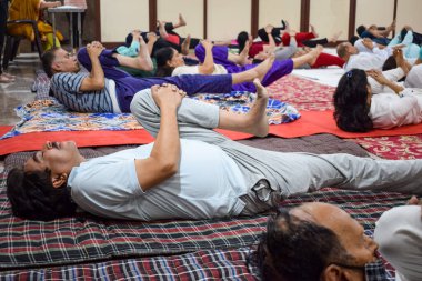 New Delhi, India, June 19 2022 -Group Yoga exercise session for people of different age groups in Balaji Temple, Vivek Vihar, International Yoga Day, Big group of adults attending yoga class in temple