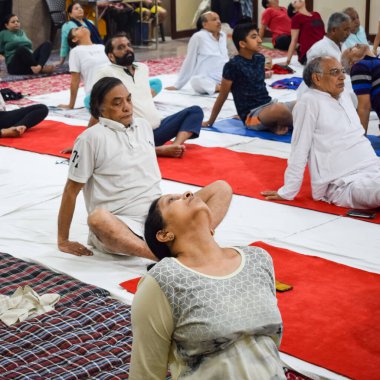 New Delhi, India, June 19 2022 -Group Yoga exercise session for people of different age groups in Balaji Temple, Vivek Vihar, International Yoga Day, Big group of adults attending yoga class in temple