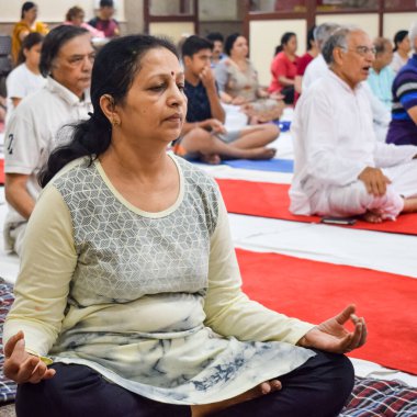 New Delhi, India, June 19 2022 -Group Yoga exercise session for people of different age groups in Balaji Temple, Vivek Vihar, International Yoga Day, Big group of adults attending yoga class in temple