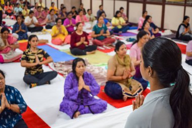 New Delhi, India, June 19 2022 -Group Yoga exercise session for people of different age groups in Balaji Temple, Vivek Vihar, International Yoga Day, Big group of adults attending yoga class in temple
