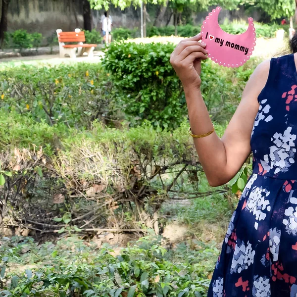 Indian couple posing for maternity baby shoot. The couple is posing in a lawn with green grass and the woman is falunting her baby bump in Lodhi Garden in New Delhi, India