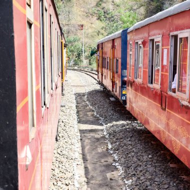 Oyuncak tren dağ yamaçlarında hareket ediyor, güzel bir manzara, bir dağ yamacı, bir vadi yamaçtan tepeye hareket ediyor, yeşil doğal ormanın arasında. Hindistan 'da Kalka' dan Shimla 'ya giden oyuncak tren, Hint treni.