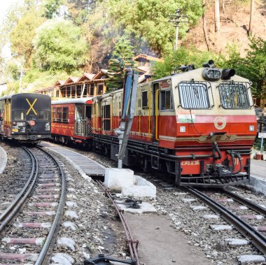 Oyuncak tren dağ yamaçlarında hareket ediyor, güzel bir manzara, bir dağ yamacı, bir vadi yamaçtan tepeye hareket ediyor, yeşil doğal ormanın arasında. Hindistan 'da Kalka' dan Shimla 'ya giden oyuncak tren, Hint treni.