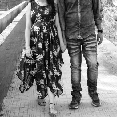 Hintli çift hamilelik çekimleri için poz veriyor. Çift yeşil çimenli bir çimenlikte poz veriyor ve kadın Yeni Delhi, Hindistan 'daki Lodhi Garden' da bebek çarpması yaşıyor.