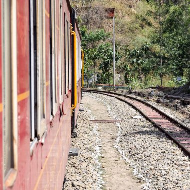 Oyuncak tren dağ yamaçlarında hareket ediyor, güzel bir manzara, bir dağ yamacı, bir vadi yamaçtan tepeye hareket ediyor, yeşil doğal ormanın arasında. Hindistan 'da Kalka' dan Shimla 'ya giden oyuncak tren, Hint treni.