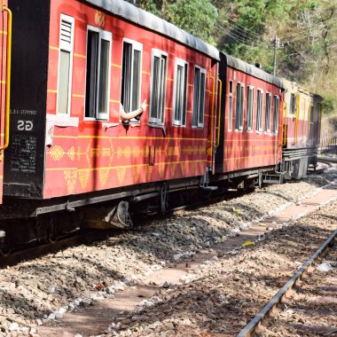 Oyuncak tren dağ yamaçlarında hareket ediyor, güzel bir manzara, bir dağ yamacı, bir vadi yamaçtan tepeye hareket ediyor, yeşil doğal ormanın arasında. Hindistan 'da Kalka' dan Shimla 'ya giden oyuncak tren, Hint treni.