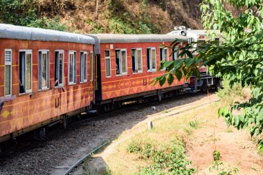 Toy Train moving on mountain slopes, beautiful view, one side mountain, one side valley moving on railway to the hill, among green natural forest. Toy train from Kalka to Shimla in India, Indian Train