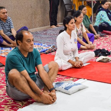 New Delhi, India, June 19 2022 -Group Yoga exercise session for people of different age groups in Balaji Temple, Vivek Vihar, International Yoga Day, Big group of adults attending yoga class in temple