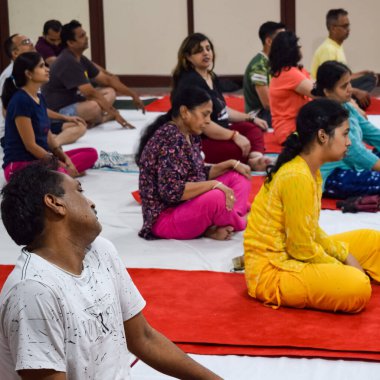 New Delhi, India, June 19 2022 -Group Yoga exercise session for people of different age groups in Balaji Temple, Vivek Vihar, International Yoga Day, Big group of adults attending yoga class in temple
