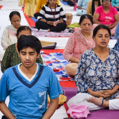 New Delhi, India, June 19 2022 -Group Yoga exercise session for people of different age groups in Balaji Temple, Vivek Vihar, International Yoga Day, Big group of adults attending yoga class in temple