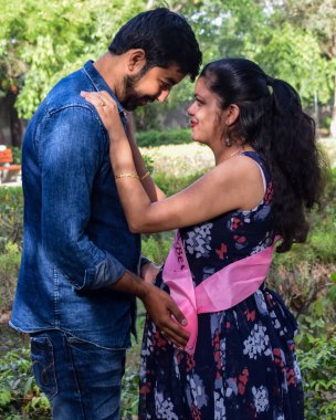 Hintli çift hamilelik çekimleri için poz veriyor. Çift yeşil çimenli bir çimenlikte poz veriyor ve kadın Hindistan, Yeni Delhi 'deki Lodhi Garden' da bebek çarpması yaşıyor.