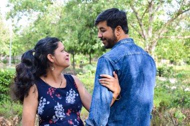 Hintli çift hamilelik çekimleri için poz veriyor. Çift yeşil çimenli bir çimenlikte poz veriyor ve kadın Hindistan, Yeni Delhi 'deki Lodhi Garden' da bebek çarpması yaşıyor.