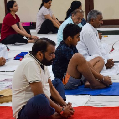 New Delhi, India, June 19 2022 -Group Yoga exercise session for people of different age groups in Balaji Temple, Vivek Vihar, International Yoga Day, Big group of adults attending yoga class in temple