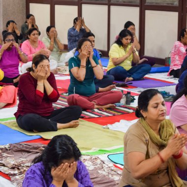 New Delhi, India, June 19 2022 -Group Yoga exercise session for people of different age groups in Balaji Temple, Vivek Vihar, International Yoga Day, Big group of adults attending yoga class in temple