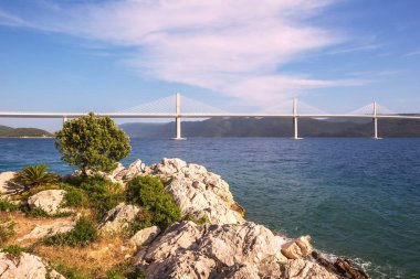 Beautiful modern bridge over the sea on Peljesac in Croatia. In the foreground houses and in the background the Peljesac mountain