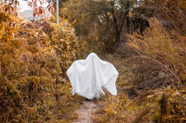 Cadılar Bayramı hayaleti gibi giyinmiş küçük bir kız. Çocuk Cadılar Bayramı 'nda hayalet kostümüyle eğleniyor..