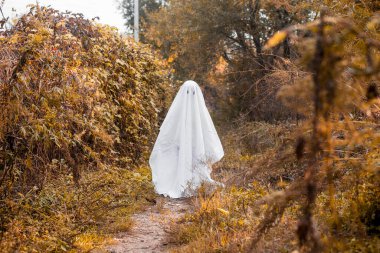 Cadılar Bayramı hayaleti gibi giyinmiş küçük bir kız. Çocuk Cadılar Bayramı 'nda hayalet kostümüyle eğleniyor..