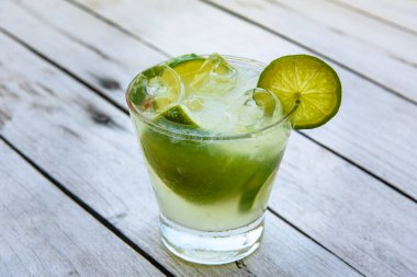 Caipirinha limonla birlikte eski ahşap bir masada içer. Tipik Brezilya içeceği cachaca, limon, buz ve şekerden yapılır..