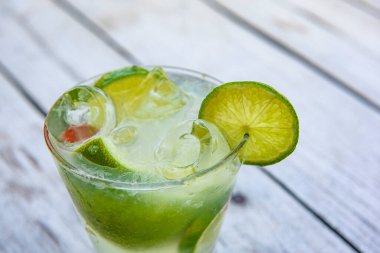 Caipirinha limonla birlikte eski ahşap bir masada içer. Tipik Brezilya içeceği cachaca, limon, buz ve şekerden yapılır..
