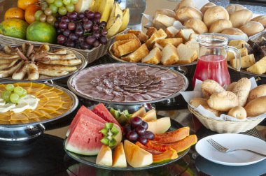 Salam, jambon, ekmek, meyve, peynir, pasta ve meyve suyu ile kahvaltı masası..