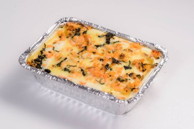 Lazanya teslimatı. Teslimat için paketlenmiş peynirli lazanya beyaz arka planda izole edilmiş..