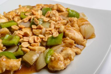 Beyaz tabakta yeşil biberli, soğanlı ve fıstıklı satranç tavuğu. Çin geleneksel yemekleri..