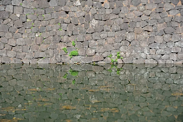 Taş duvar ve su yüzeyindeki yansıması..