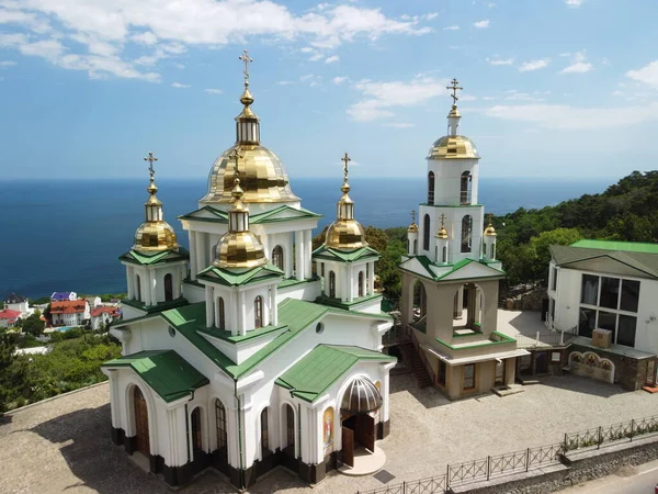 Christian church on a background of mountains. Temple of the Holy Archangel Michael in Oreanda. The southern coast of Crimea. Located on a rocky cliff and is surrounded by beautiful vegetation