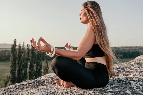 Young woman with black hair, fitness instructor in pink sports leggings and tops, doing pilates on yoga mat with magic pilates ring by the sea on the beach. Female fitness daily yoga concept