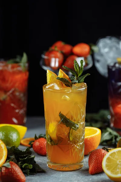 Színes frissítő italok nyárra, hideg eper limonádé lé jégkockákkal a poharakban, szeletelt friss citrommal díszítve. — Stock Fotó