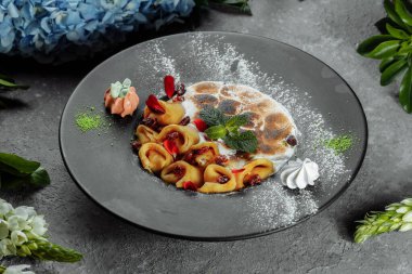 Karamelli fındık ve bademle servis edilen portakal soslu peynirli krepler. İştah açıcı yemek. Mutfak fotoğrafçılığı, yemek servisi teklifi..