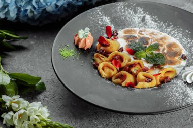 Karamelli fındık ve bademle servis edilen portakal soslu peynirli krepler. İştah açıcı yemek. Mutfak fotoğrafçılığı, yemek servisi teklifi.