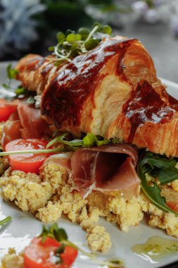 Jambonlu, peynirli ve tabakta çırpılmış yumurtalı enfes kruvasan sandviçi..