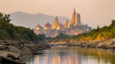 Time lapse of Tiger Cave Temple, Kanchanaburi, Thailand is a popular place for tourists. View from the canal at sunset unseen and amazing