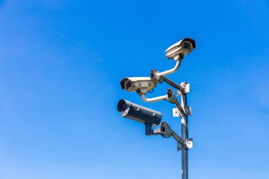 Eski güvenlik kamerası ya da CCTV, gökyüzü arkaplanı olan bir direkte oturur..