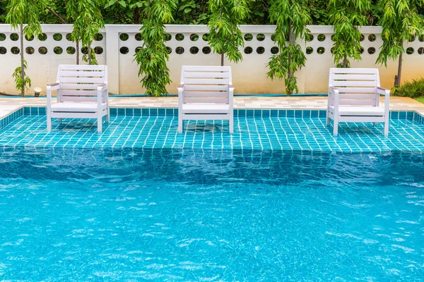 White chairs in the pool line up to sit and relax.