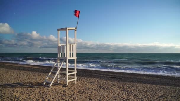 Weißer hölzerner Beobachtungsposten für Rettungsschwimmer an einem Sandstrand mit Wellen. Das Konzept der Einheit mit der Natur.