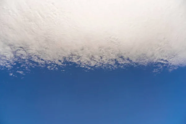 Puszyste chmury na niebieskim niebie, są rozmieszczone w płaskim pasie. — Zdjęcie stockowe