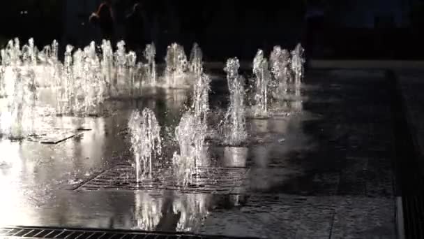 Vannstråler fra byens fontene i parken i solnedgangen. Vanntrykk og trykk. Ødelegger vann. Langsom bevegelse. Lukk – stockvideo