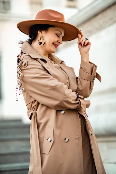 Εξωτερικό πορτρέτο μόδας των νέων κομψό μοντέρνα μελαχρινή γυναίκα, μοντέλο σε κομψό καπέλο, τσόκερ και ελαφρύ αδιάβροχο ποζάρουν στο ηλιοβασίλεμα στην ευρωπαϊκή πόλη. — Φωτογραφία Αρχείου