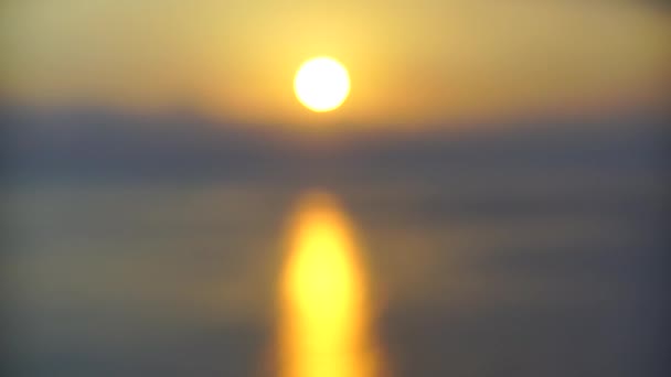 Superficie del mar pequeñas olas contra la salida del sol en cámara lenta dorada. Gran disco del sol se eleva sobre el fondo borroso del mar, sendero soleado en el agua, nubes. Luz dorada del panorama marino. Relájate. — Vídeo de stock