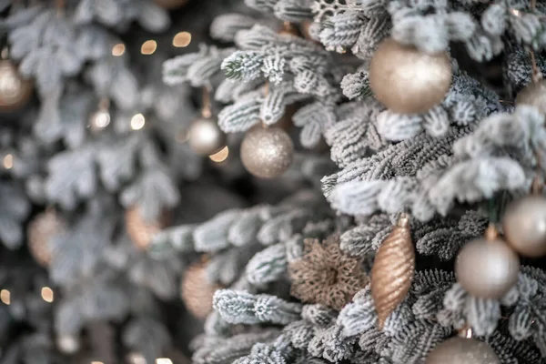 Närbild av en festligt dekorerad utomhus julgran med bollar på en suddig gnistrande älva bakgrund. Oskärpa körtelbelysning, bokeh effekt. — Stockfoto