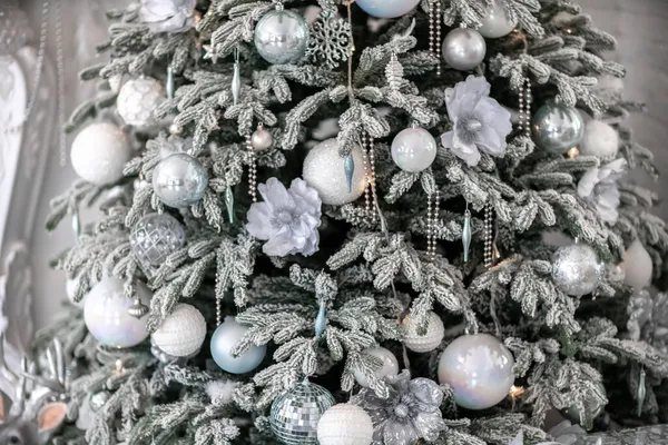 Närbild av en festligt dekorerad utomhus julgran med bollar på en suddig gnistrande älva bakgrund. Oskärpa körtelbelysning, bokeh effekt. — Stockfoto