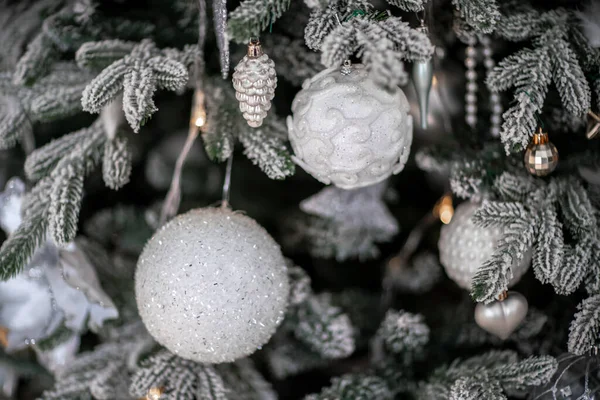 Close-up de uma árvore de Natal ao ar livre festivamente decorada com bolas em um fundo de fadas espumante borrado. Luzes de guirlanda desfocadas, efeito bokeh. — Fotografia de Stock