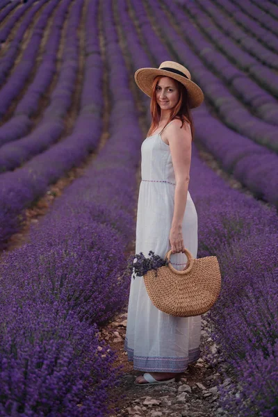 Charmante jeune femme avec un chapeau et robe blanche dans un champ de lavande pourpre. Style de vie à l'extérieur. Vue arrière — Photo